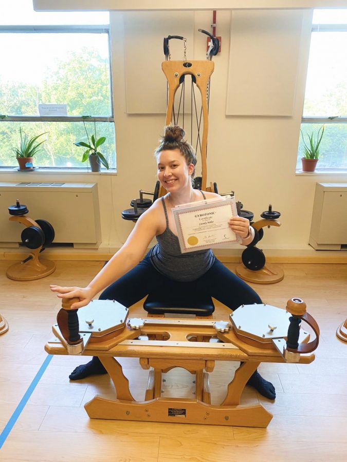 Miller poses with her GYROTONIC® certificate,while sitting on one of the machines. 