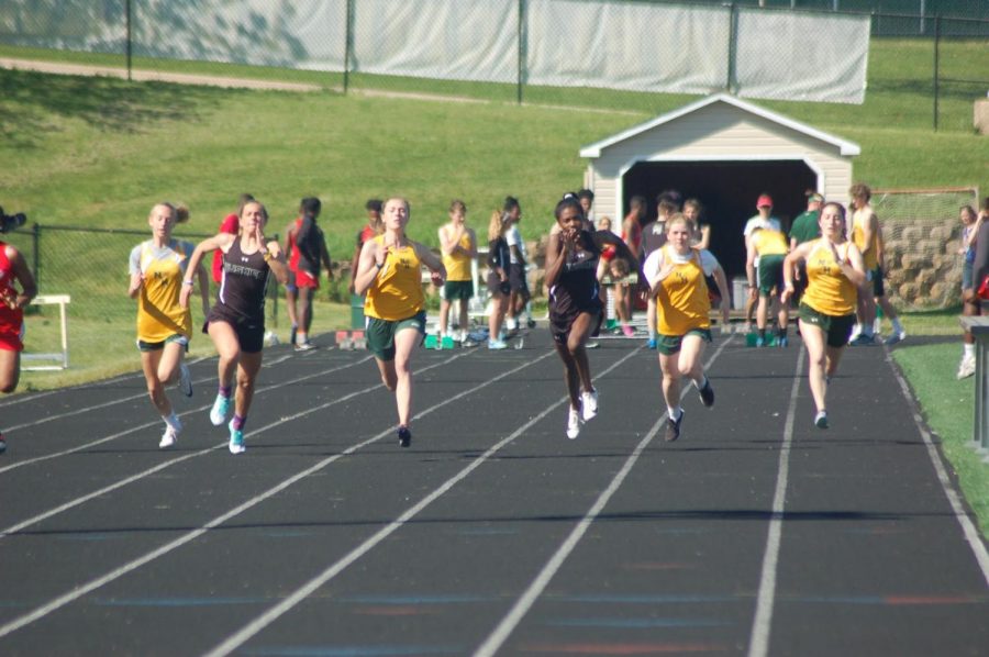 Girls from previous years run in a home meet. For meets this year, runners and participants would be required to wear masks.