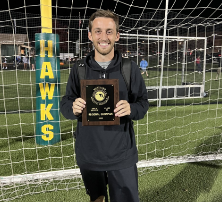 Riordan helped the team win their 2022 regional title versus Harford Tech. He poses with the Hawks plaque. 