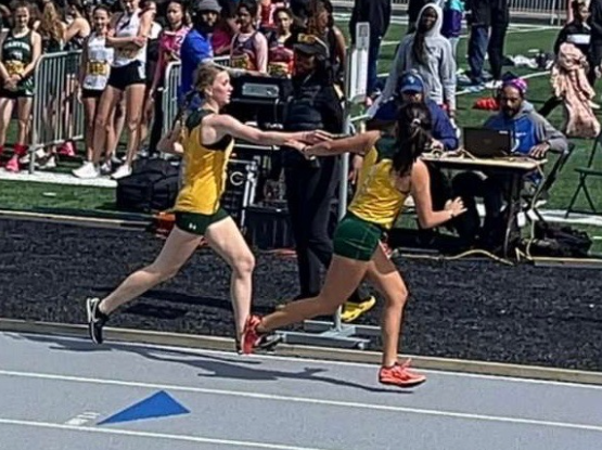 Freshman Madilyn Coyle and senior Valentina Angulo perform a handoff in a relay. They ran on Saturday April 13 at Towson University. 